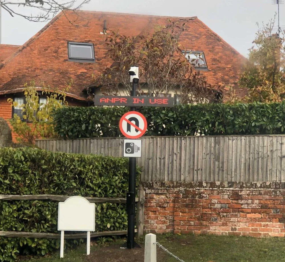 Pole-mounted ANPR camera and red LED matrix display showing "ANPR IN USE" at a site entrance