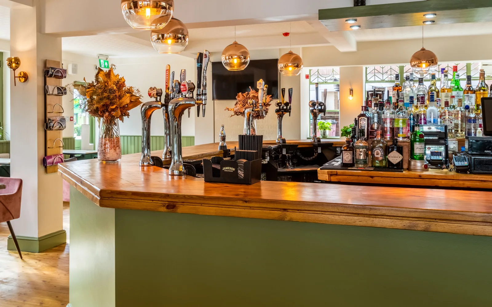A pub bar counter with hand pumps, the spirits shelf behind it and the floor beyond